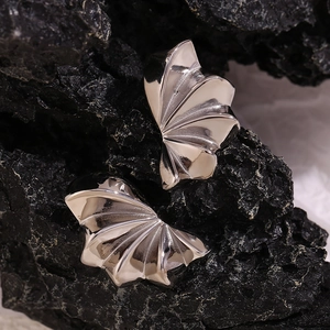 Macro shot of silver petal-shaped abstract earrings on a dark natural rock surface