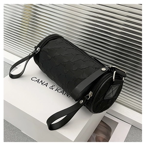 Detail of black cylindrical crossbody bag with textured bubble fabric and brand box