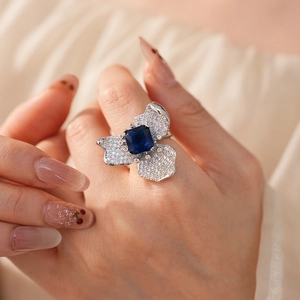 Detailed macro of a silver floral ring featuring a square blue zircon and pavé stones