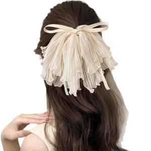 Elegant beige mesh bow hair claw clip with pearl accents shown on woman's hair