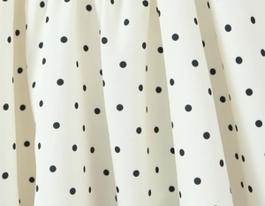 Close-up of white polka dot fabric texture with soft drapes and smooth finish