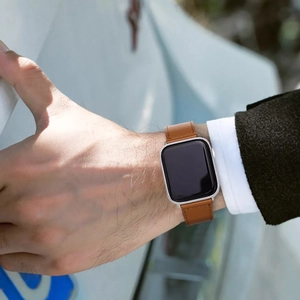 Classic brown leather strap with stitching on a silver smart watch worn outdoors