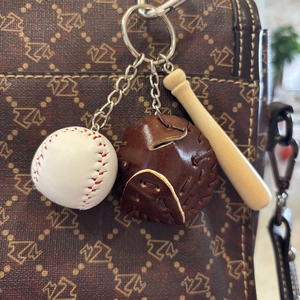 Detailed close-up of a mini baseball keychain set with glove and bat on a luxury bag