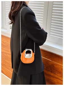Close-up of mini orange patent leather crossbody bag with silver chain and metal handle