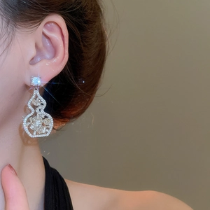 Close-up of sparkling silver hollow gourd earrings with floral patterns and zircons