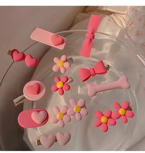 Close-up of 12-piece pink heart and flower matte resin hair clips set in glass dish