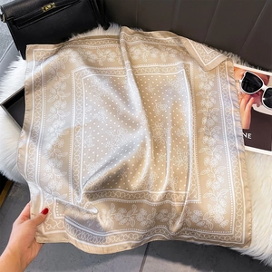 Dettaglio della texture del foulard di seta color champagne con motivi floreali su pelliccia