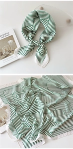 Detail showing white and green geometric pattern on a light square silk scarf