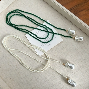 Detail view of long pearl necklace with green spinel beads and baroque pearl drop pendant