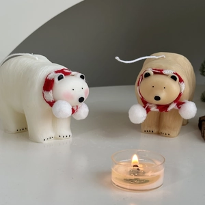 Detail of white polar bear candles wearing red and white striped scarves for decoration