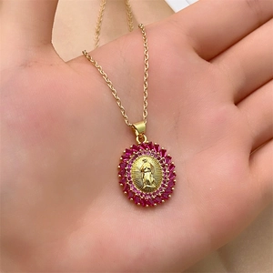 Close-up of Virgin Mary pendant with pink gemstones held in hand for scale