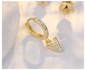 Close-up of golden S925 silver hoop earring with V-shaped letter pendant and white zircons