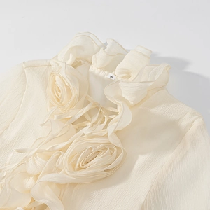 Close-up of cream white lantern sleeve dress with 3D floral pleated neck detail