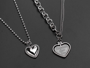 Close-up of double layer heart pendant necklaces in silver steel with engraved text