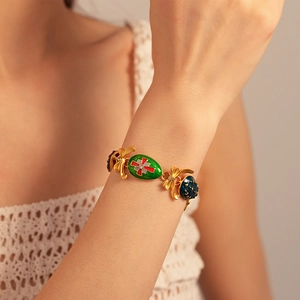 Close-up of vintage gold bracelet with colorful enamel pendants and bow details