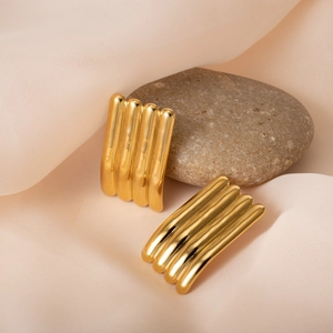 Detailed macro view of gold ribbed titanium earrings on silk fabric background