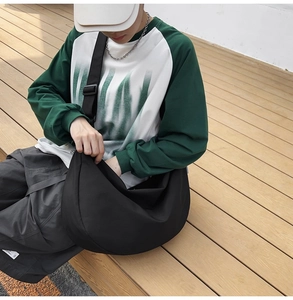 Outdoor shot of a black nylon crossbody bag showing its large capacity and crescent shape
