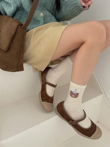 Detailed close-up of cream cotton socks with colorful specks and a teddy bear embroidery