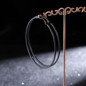 Detail view of large matte black hoop earrings on a vintage metal display stand