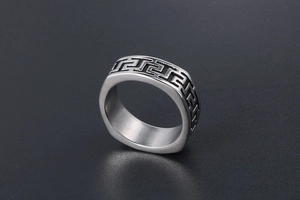 Macro shot of silver titanium steel ring featuring an engraved classic Greek Key pattern