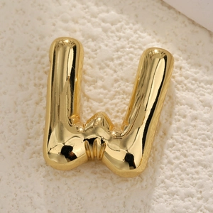 Macro close-up of golden bubble letter W pendant with a polished finish and smooth surface