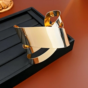 Macro shot of an irregular gold twisted metal bangle on a black jewelry display stand