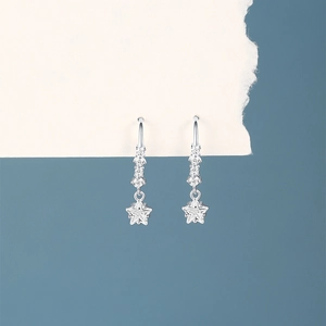 Macro detail of star-shaped silver drop earring with shimmering clear cubic zirconia