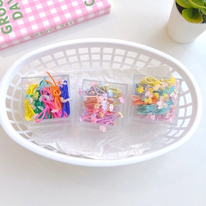 Macro detail of colorful children hair ties with floral and bear charms in a mini basket