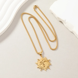 Detail of a golden sun face pendant with a box chain on white decorative stone