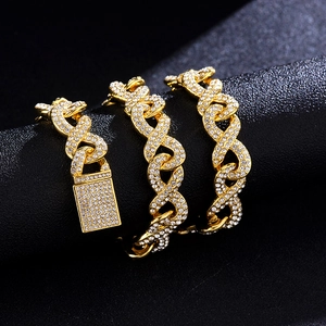Close-up of gold Cuban link bracelet with iced-out padlock charm on black texture