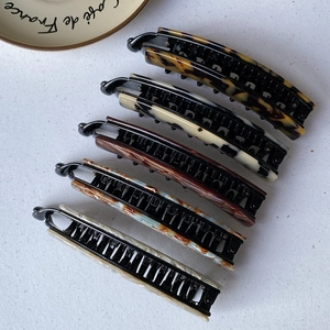 Detail view showing five leopard and marble pattern large banana hair clips with teeth