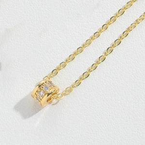 Makroaufnahme einer goldenen Zylinder-Halskette mit funkelnden Zirkonia-Steinen