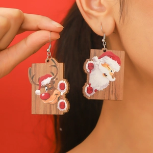 Detail view of Santa and reindeer wooden Christmas earrings on a warm red background