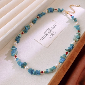 Detailed shot of Bohemian beaded necklace with blue stones, pearls, and gold spacers