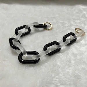 Detail of acrylic bee chain with black and translucent frosted links and gold ring clasps