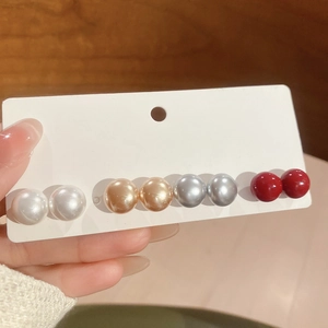 Close-up of four pairs of colorful pearl stud earrings on a display card