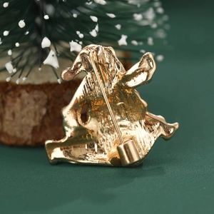 Golden Santa Claus enamel brooch pin shown from the back against a green festive tree