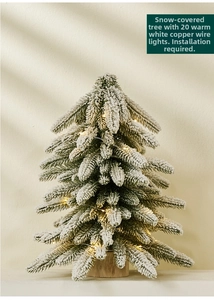 Close-up of 40cm mini snowy Christmas tree with warm LED lights and solid wooden base