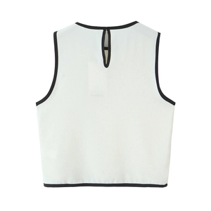 Detail view of white sleeveless top featuring black contrast piping and back button closure
