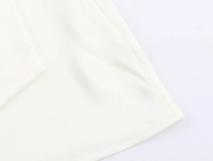 Macro-detail van de gladde witte satijnen stoftextuur en precieze stiksels op de jurk