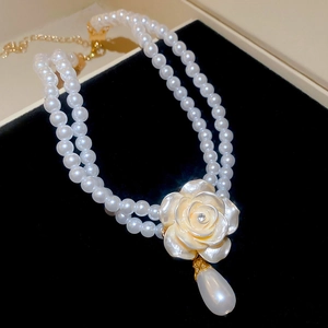 Détail du collier de perles double rang avec pendentif fleur et perle en forme de goutte