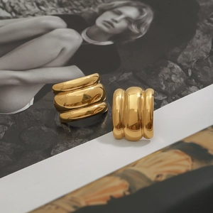 Macro shot of thick gold hoop earrings with a mirror polished finish on an artistic background