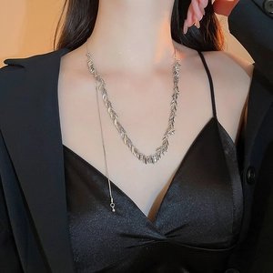 Collana con nappine a foglia d'argento indossata da una modella con blazer nero