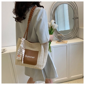 Détail d'un cabas en paille tressée avec texte Summer et foulard géométrique chic