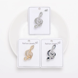 Detailed macro view of musical note brooches with crystal inlay in gold and silver finishes