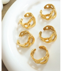 Macro shot of five gold chunky chain links rings on a white porcelain dish
