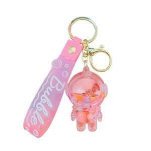 Pink astronaut keychain with liquid quicksand bottle and acrylic pendant on white background