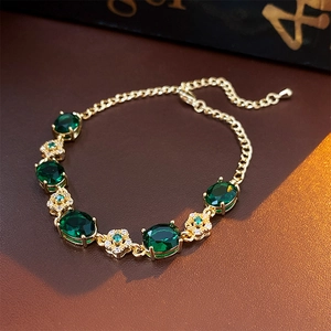 Detail of gold flower bracelet with emerald green stones and white diamond accents