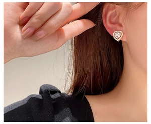 Close-up of model wearing gold-framed heart stud earrings with sparkling cubic zirconia