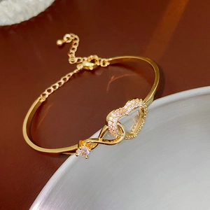 Macro view of gold-plated heart and infinity bracelet featuring sparkling zircon stones